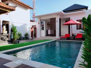 a villa with a swimming pool in front of a house at Pondok DenAyu Homestay in Kuta