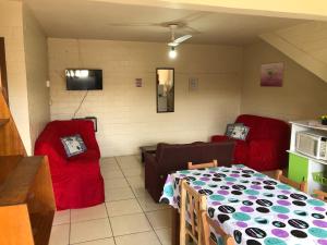 a living room with two red chairs and a table at Residencial BomAluguel in Capão da Canoa