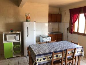a kitchen with a table and a white refrigerator at Residencial BomAluguel in Capão da Canoa