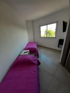 two beds in a room with purple sheets and a window at Departamento nuevo 2 dorm, parrilla, cochera in Neuquén