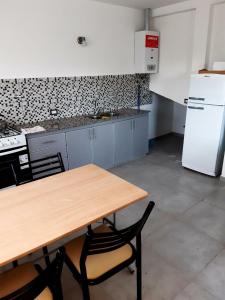 a kitchen with a wooden table and a white refrigerator at Departamento nuevo 2 dorm, parrilla, cochera in Neuquén