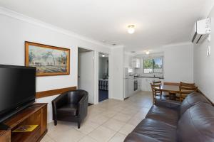 een woonkamer met een leren bank en een televisie bij Apollo Lodge in Toowoomba