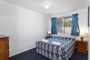 a bedroom with a bed and a window with blue curtains at Apollo Lodge in Toowoomba
