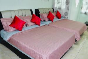 two beds with red pillows sitting next to each other at LILY VACATION HOME at CAMERON HIGHLANDS - 12 PAX,FREE WiFi w CARPORCH in Tanah Rata