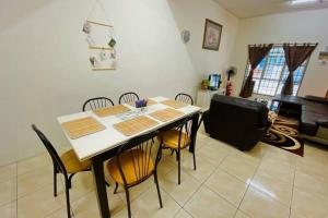 LILY VACATION HOME at CAMERON HIGHLANDS - 12 PAX,FREE WiFi w CARPORCH في تاناه راتا: طاولة طعام وكراسي في الغرفة