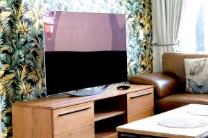 uma televisão de ecrã plano numa bancada de madeira numa sala de estar em Rockwell 304 em Cidade do Cabo