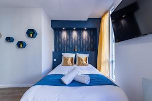 a bedroom with a blue and white bed with pillows at L'Alcôve Dorée - Appart'Hôtel SPA - Melina & Alfred Agen in Agen