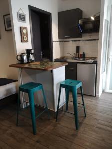 a kitchen with two green stools next to a counter at La Compagnie des 5 Mondes in Saint-Nazaire