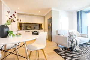 uma cozinha e sala de estar com uma mesa branca e cadeiras em KOZYGURU DOCKLANDS MODERN COZY 1 BED ROOM UNIT MELBOURNE VDO628 em Melbourne