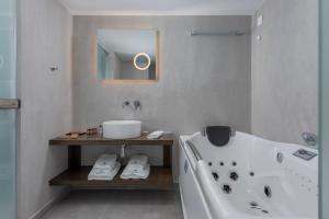 a bathroom with a tub and a sink and a mirror at LaLiBay Resort & Spa - Adults Only in Perdika