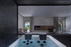 a bath tub in a room with a large window at LaLiBay Resort & Spa - Adults Only in Perdika