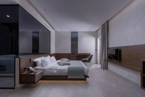 a bedroom with a bed and a desk and a television at LaLiBay Resort & Spa - Adults Only in Perdika