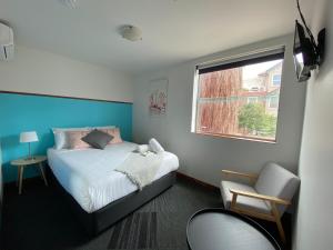 a bedroom with a bed and a window and a chair at Nomads St Kilda - Base in Melbourne