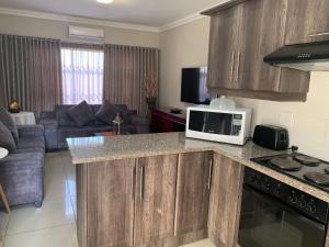 a kitchen with a microwave and a living room at Bay Sun Lodge in Richards Bay