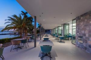 a restaurant with tables and chairs and the ocean at LaLiBay Resort & Spa - Adults Only in Perdika