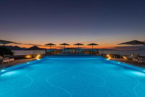 a swimming pool with a view of the ocean at night at LaLiBay Resort & Spa - Adults Only in Perdika