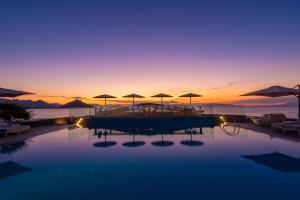 a pool with tables and umbrellas at sunset at LaLiBay Resort & Spa - Adults Only in Perdika