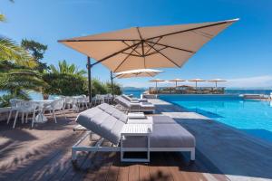 a pool with tables and chairs and a large umbrella at LaLiBay Resort & Spa - Adults Only in Perdika