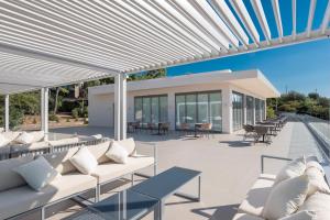 an outdoor patio with white couches and tables at LaLiBay Resort & Spa - Adults Only in Perdika