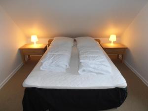 a large bed with two lights on two tables at Blåvand in Blåvand