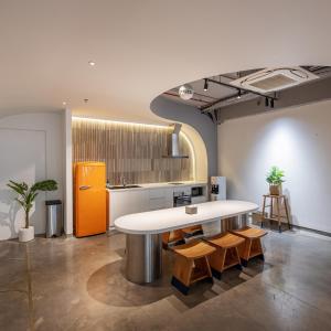 a kitchen with a large white counter and wooden chairs at Meander Saigon in Ho Chi Minh City