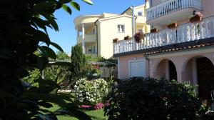 budynek z balkonem i kwiatami na dziedzińcu w obiekcie Apartments Ravlic w mieście Malinska