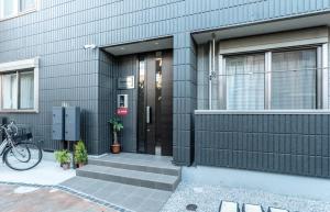 東京的住宿－Shibuya 渋谷 下北沢エリア 電動キックボードLUUP敷地内 駅徒歩3分，一座有黑色门的房子和一辆自行车停在外面