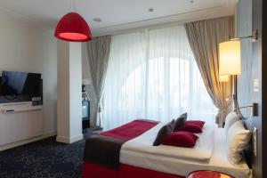 a hotel room with a large bed with red pillows at Mercure Rostov-On-Don Center in Rostov on Don
