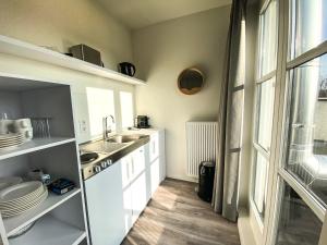 cocina con armarios blancos, fregadero y ventana en Appartement Centrum Domburg DO06, en Domburg