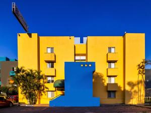 Um edifício amarelo com um objecto azul à frente. em Suites Navata em Guadalajara