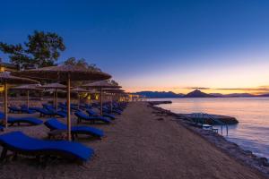a row of blue chairs and umbrellas on a beach at LaLiBay Resort & Spa - Adults Only in Perdika