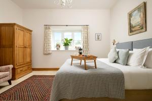 Un dormitorio con una cama con una mesa. en Barrow Hill Barns en Petersfield
