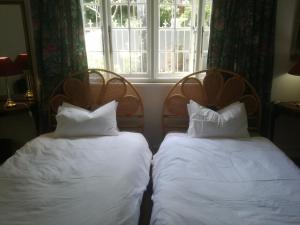 two beds with pillows in a room with a window at Valley Guest House in Port Elizabeth
