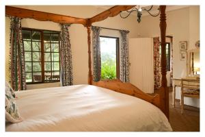 1 dormitorio con cama con dosel y ventanas en TOAD HALL SELF CATERING COTTAGES. en Lidgetton