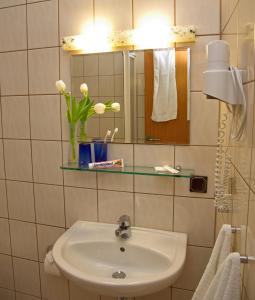 a bathroom with a sink and a mirror and flowers at Stadtcafé Hotel garni in Hammelburg