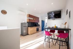 a kitchen with a table and two pink bar stools at Mieuxqualhotel jacuzzi privatif Le carré in Bordeaux