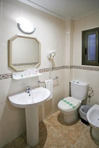 
a bathroom with a toilet, sink, and mirror at Hotel Canadá in Tarragona
