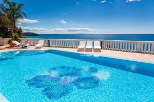 a beach scene with a blue pool and blue chairs at Grand Hotel Le Rocce in Gaeta