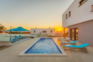 a swimming pool with lounge chairs and umbrellas next to a building at Villa LEA MAGDALENA in Malinska