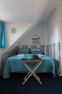 um quarto com uma cama azul e uma mesa em Bed & Breakfast Hotel Zandvoort em Zandvoort