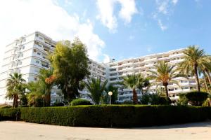 a large white building with palm trees in front of it at Apartamento Can Poma in Alcudia