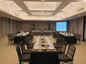 a conference room with tables and chairs and a screen at Krabi La Playa Resort - SHA Plus in Ao Nang Beach