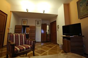 a living room with a flat screen tv and a chair at Apartments & Rooms Vienna in Osijek