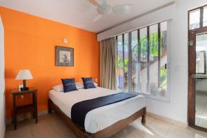 una camera da letto con pareti arancioni, un letto e una finestra di Hotel Misión y Spa ad Acapulco