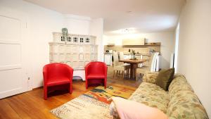 a living room with a couch and two red chairs at Ferienwohnung am Wasserschloss 1-3 in Ochsenfurt