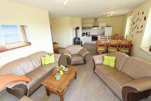 a living room with couches and a table and a kitchen at Haus am Deich Feriendomizil mit Terrasse in Baabe +21 photos