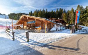 ein Blockhaus im Schnee vor einer Straße in der Unterkunft Alpengasthof Götschenalm in Bischofswiesen