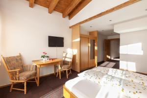 Habitación de hotel con cama, escritorio y TV. en Alpengasthof Götschenalm, en Bischofswiesen