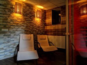 a porch with two chairs and a table and a stone wall at Chata DESMO in Prkenný Dŭl