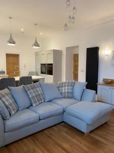 a living room with a blue couch and a kitchen at Wells House luxury 2 bedroom apartment in Harrogate